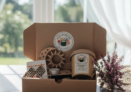 Gift box with 'Wild Wonders' products including a candle, coaster, and card on a wooden surface.