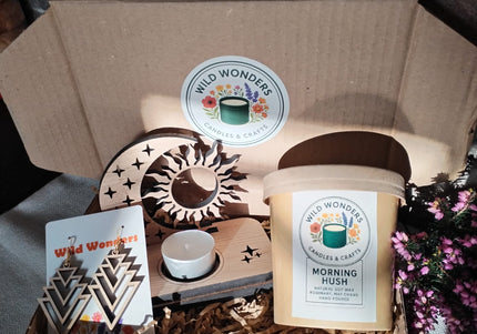 Gift box with candles, decor items, and a card on a stone surface