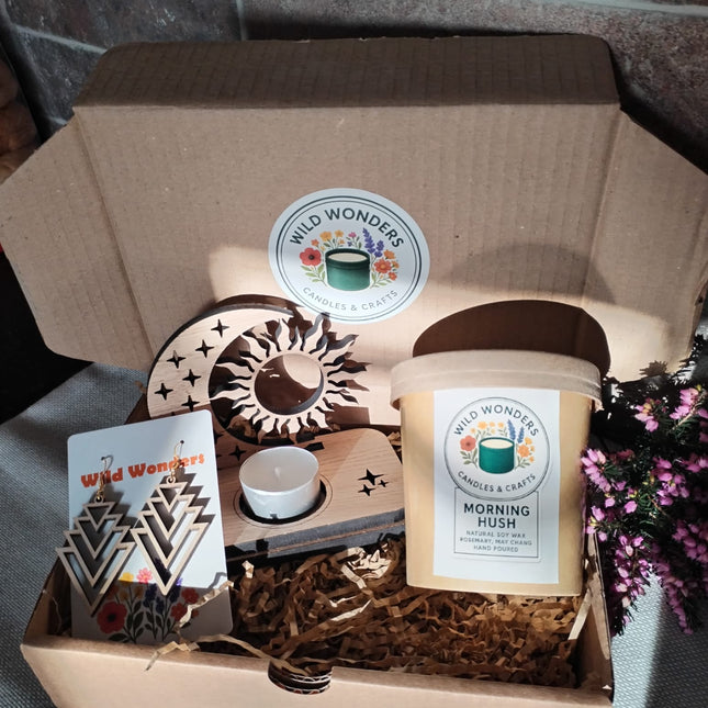 Gift box with candles, decor items, and a card on a stone surface