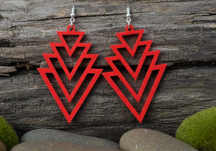 Red geometric earrings on a wooden surface with stones and moss