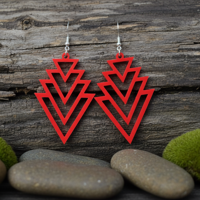 Red geometric earrings on a wooden surface with stones and moss