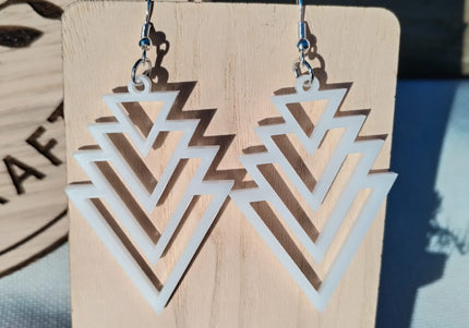 Geometric earrings on a wooden display card with a blurred background