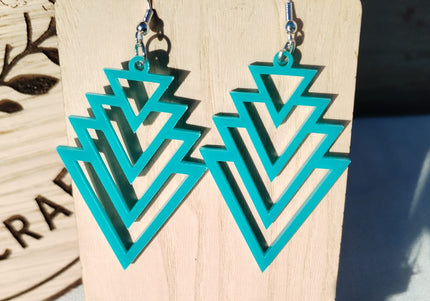 Turquoise geometric earrings on a wooden stand with a blurred background