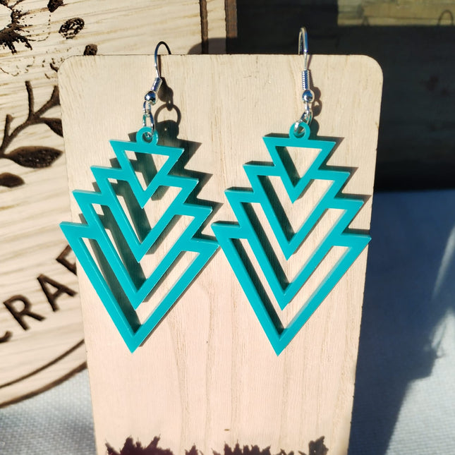 Turquoise geometric earrings on a wooden stand with a blurred background