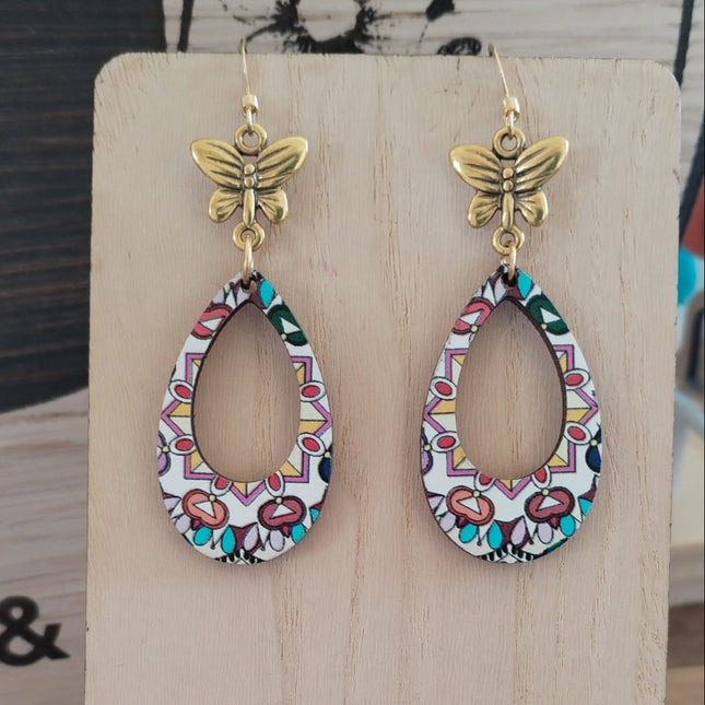 Butterfly-shaped earrings on a wooden display stand with a blurred background.