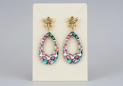 Pair of colorful earrings on a beige card against a gray background