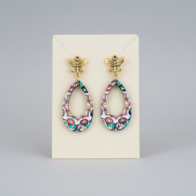 Pair of colorful earrings on a beige card against a gray background