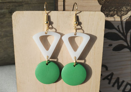 Green and white triangle earrings on a wooden stand with a floral background