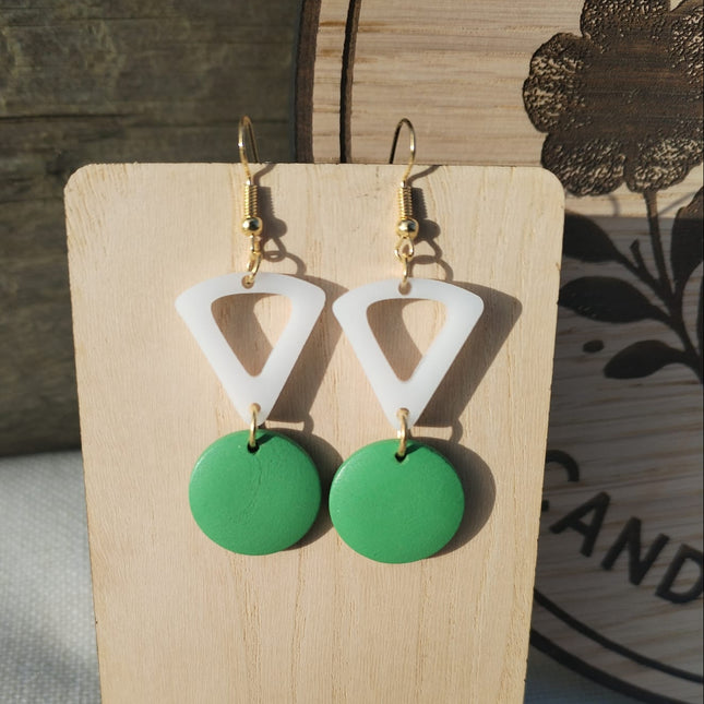 Green and white triangle earrings on a wooden stand with a floral background
