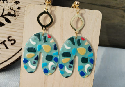 Colorful patterned earrings on a wooden stand with a blurred background
