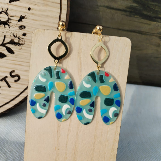 Colorful patterned earrings on a wooden stand with a blurred background