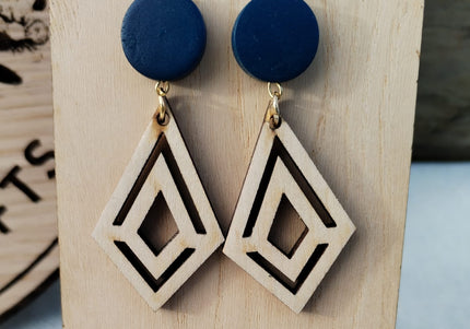 Pair of blue and geometric wooden earrings on a wooden stand with a blurred background.
