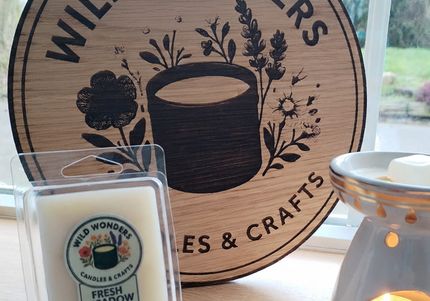 Wild Wonders candles and diffuser on a table with a branded wooden sign in the background.