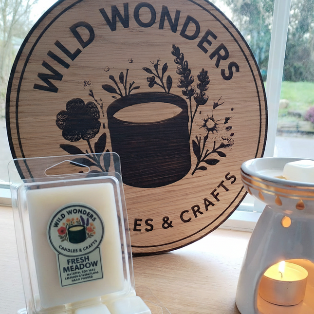 Wild Wonders candles and diffuser on a table with a branded wooden sign in the background.