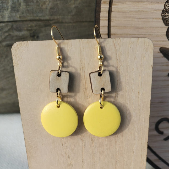 Yellow earrings on a wooden stand with a floral background