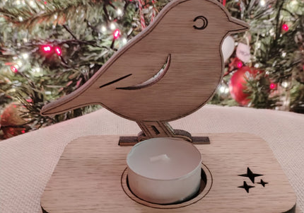 Wooden bird-shaped holder with a small candle on a textured surface with a Christmas tree in the background.