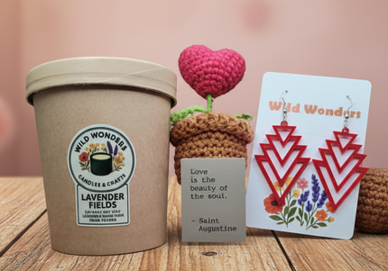 Cup of lavender ice cream with a card and small crocheted plants on a wooden surface.
