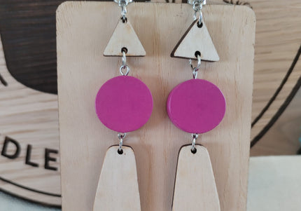 Pair of earrings with pink and wooden geometric shapes on a wooden display card.