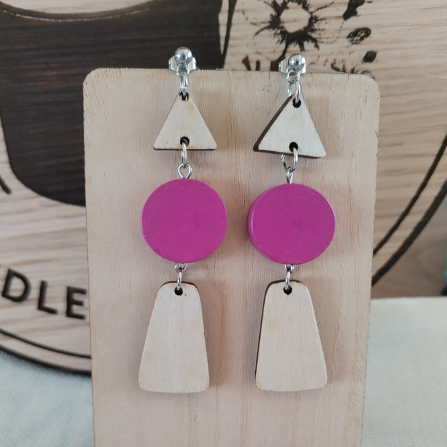 Pair of earrings with pink and wooden geometric shapes on a wooden display card.